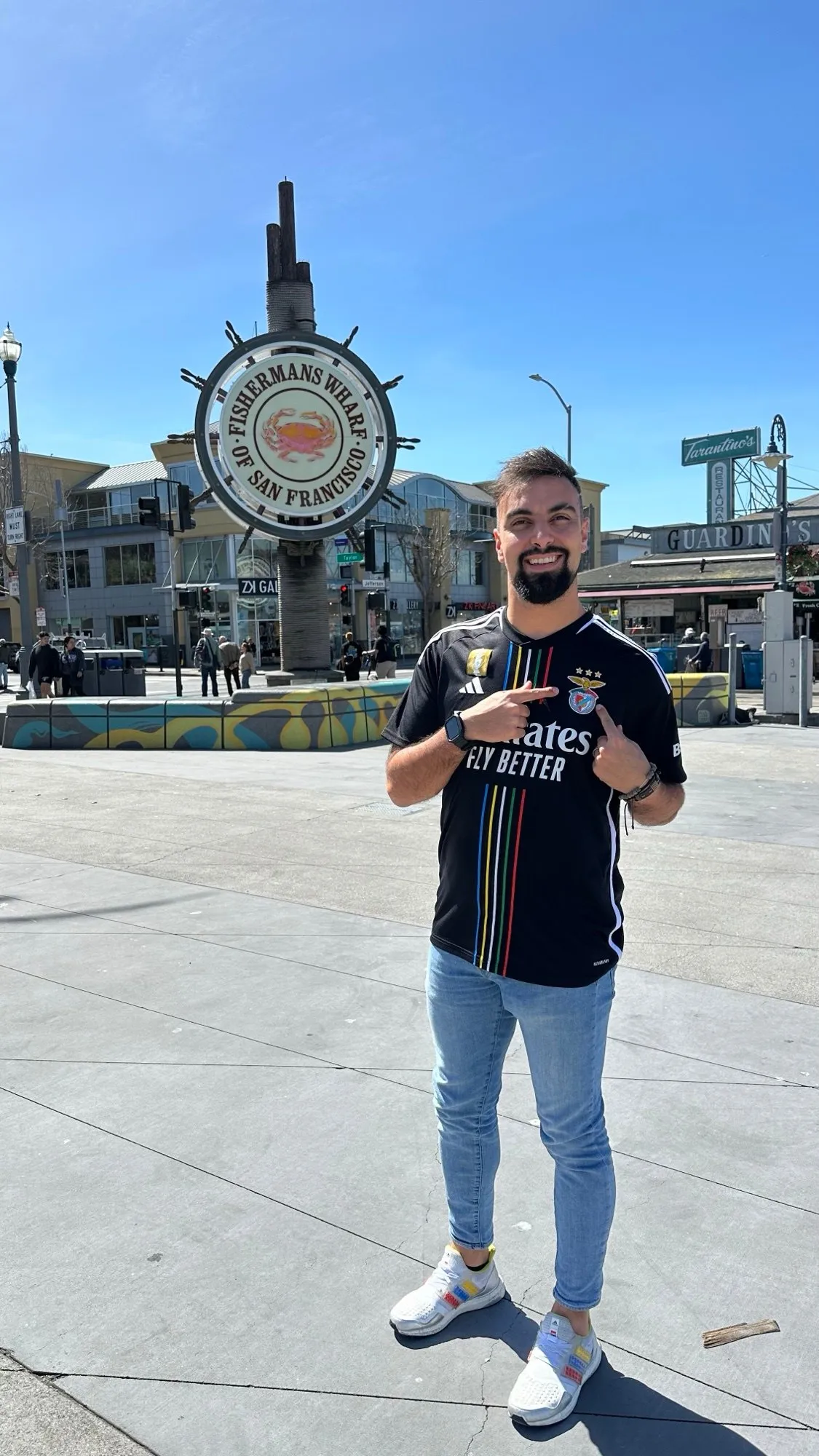 David Olim in San Francisco, smiling and pointing at the badge on his football shirt