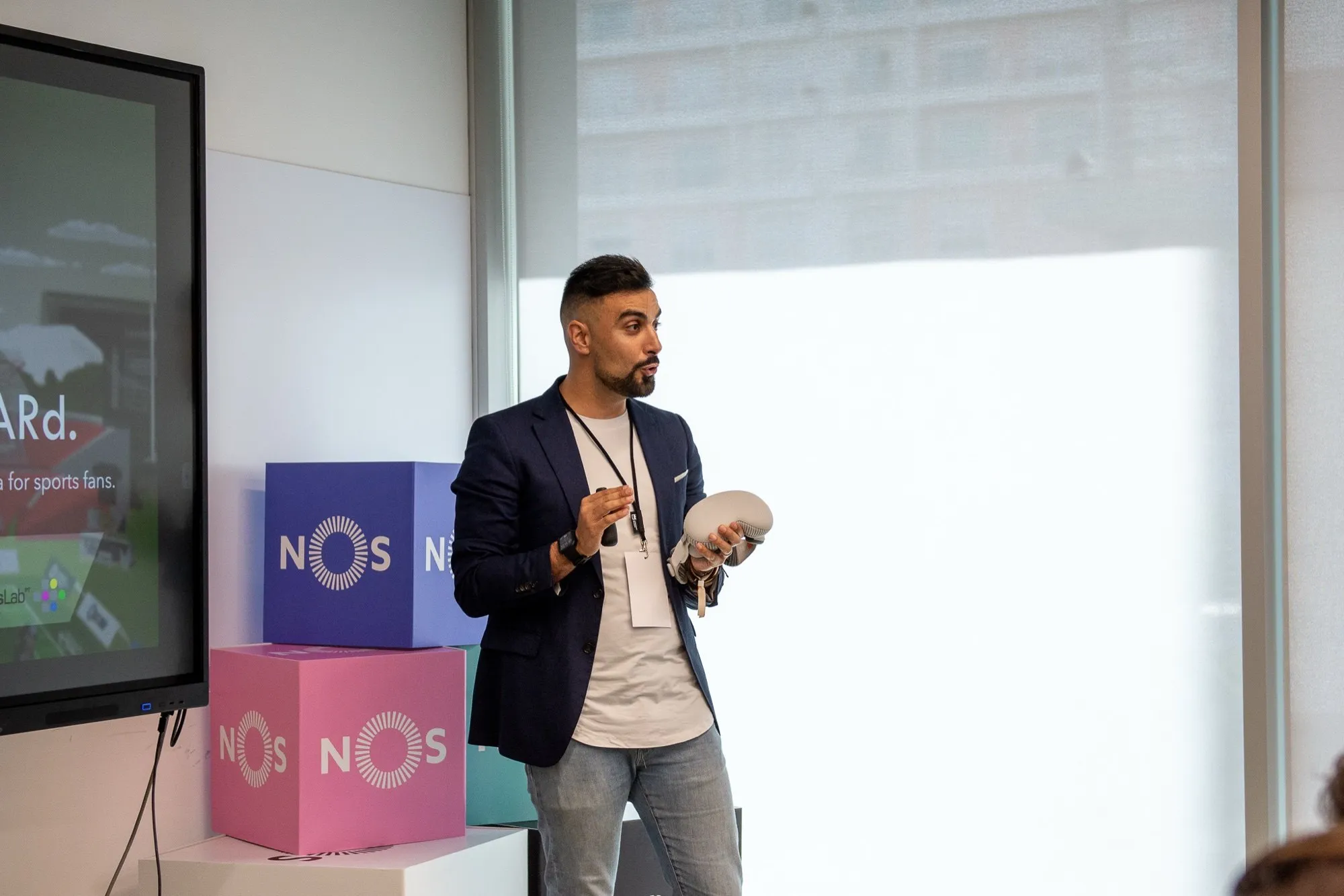 David Olim speaking beside a screen and NOS-branded boxes